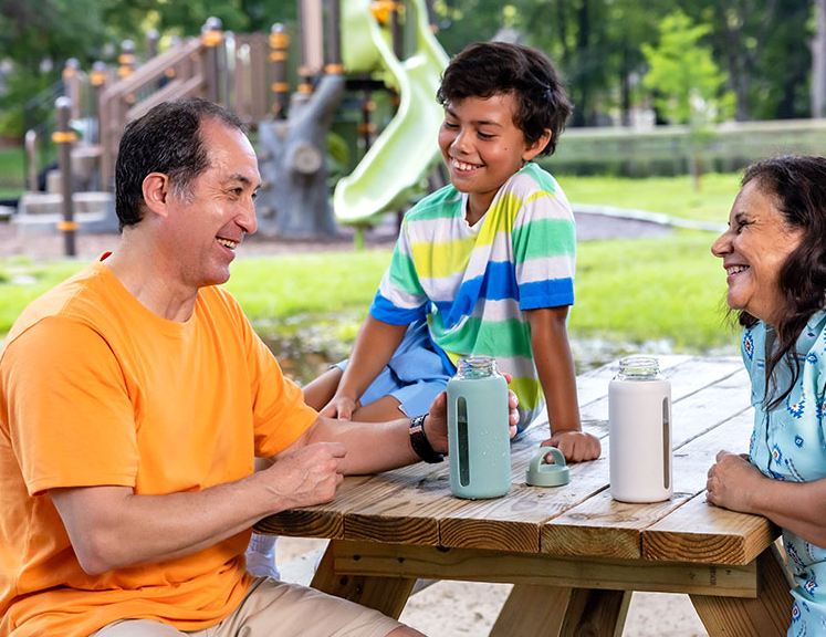 Grandparents sitting at a picnic table and talking with their grandson